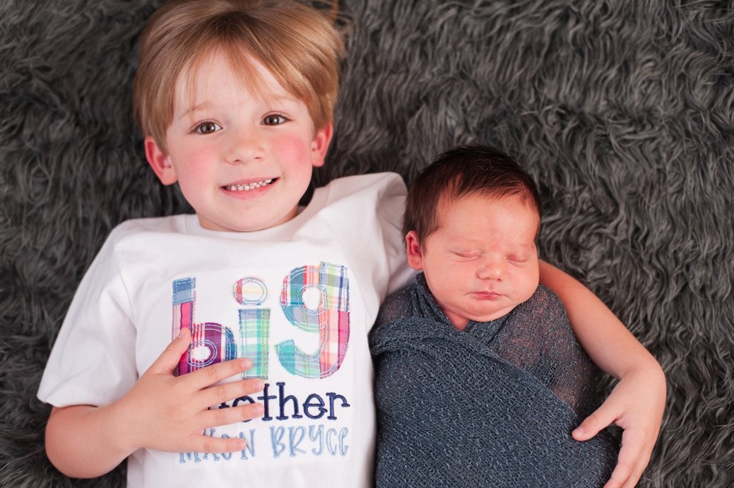 big brother and baby in swaddle